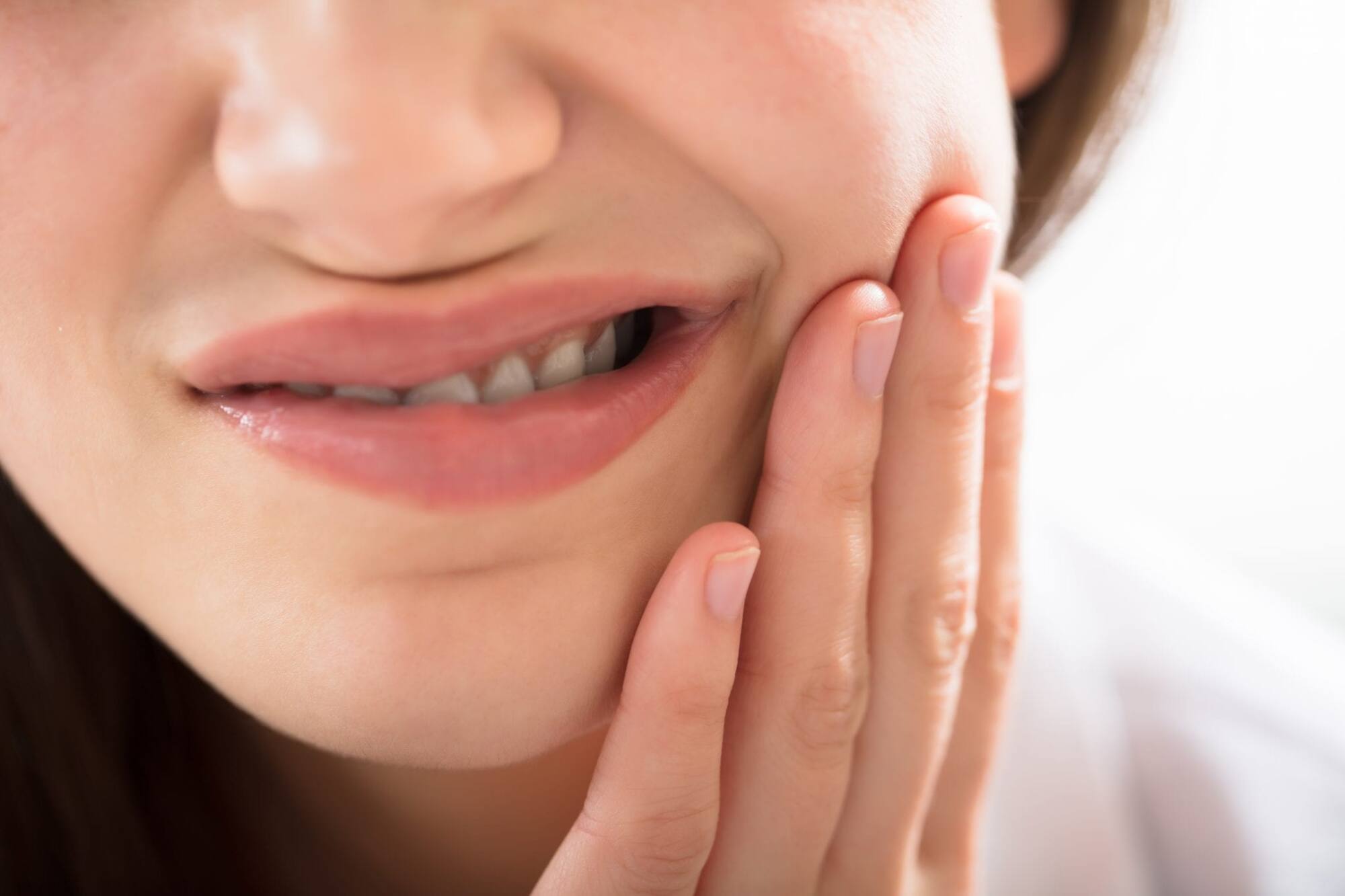 Young woman feeling pain in her teeth due to sensitivity